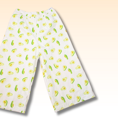 white wide leg pants with avocado print on a pastel yellow background.