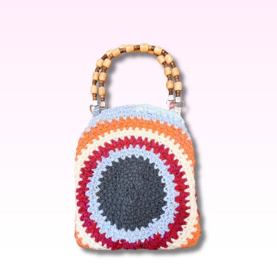 Colorful crocheted handbag with wooden handle on a light purple background