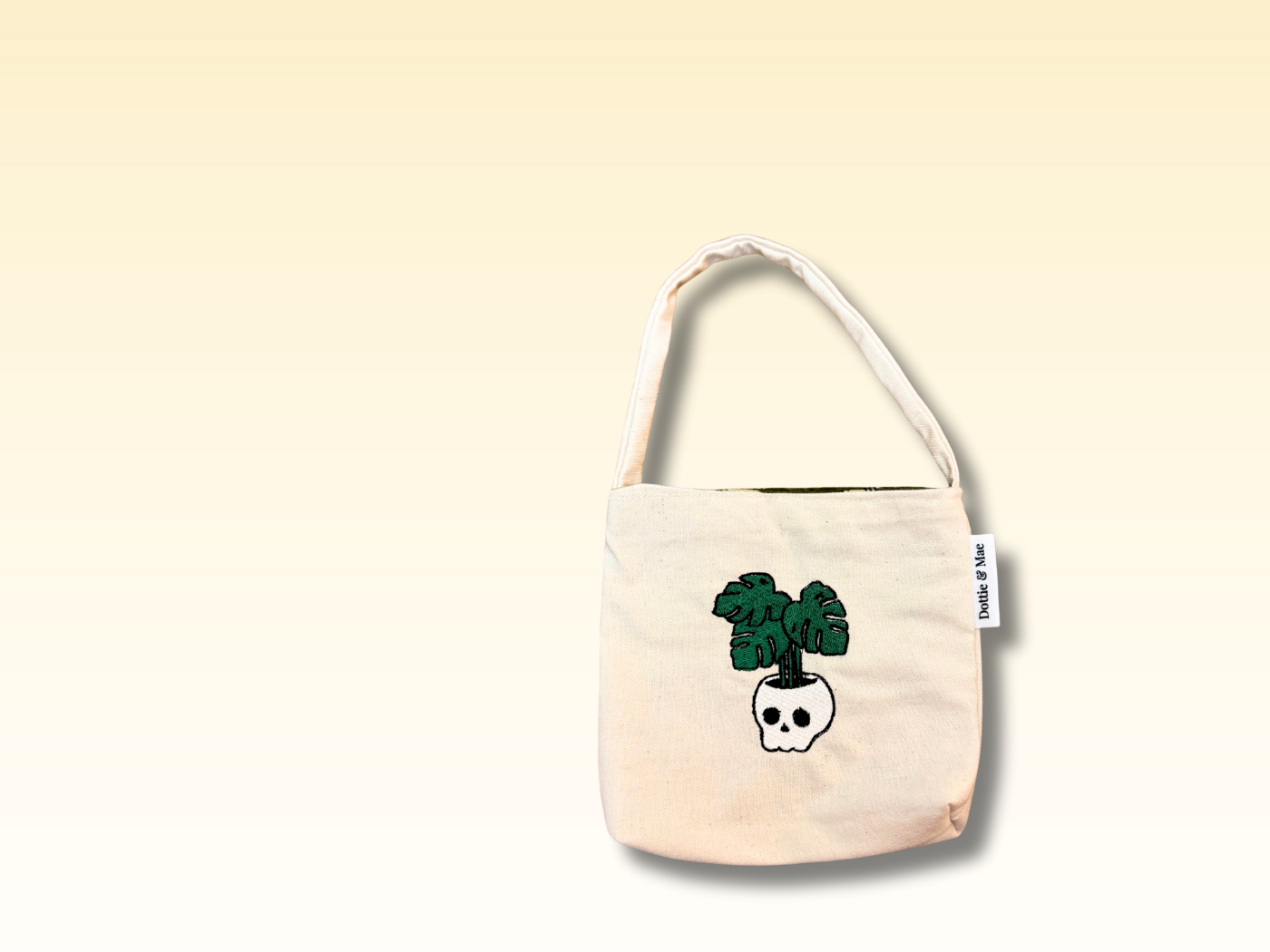 Beige tote bag with a skull and plant design on a beige background
